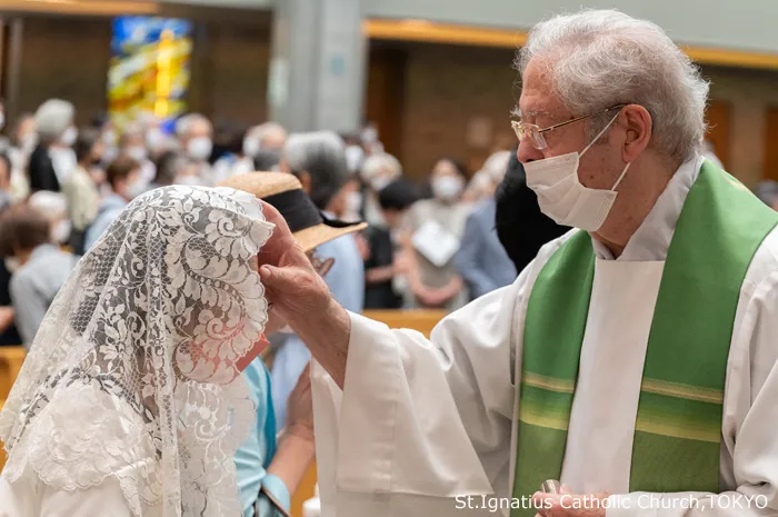 ベールの女性に塗油をするガラルダ神父
