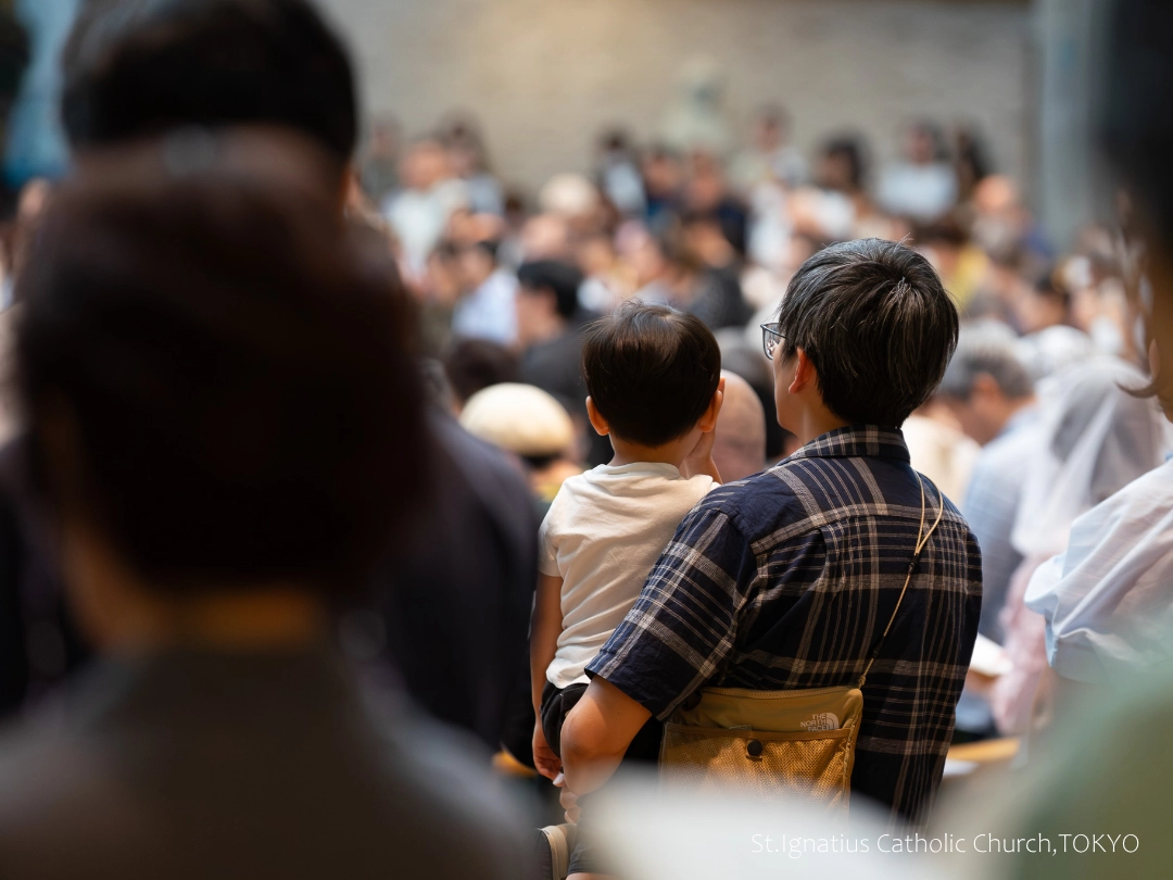 9/13(日)10:00- 年間第24主日 会衆席の親子。男の子を抱っこする父親。