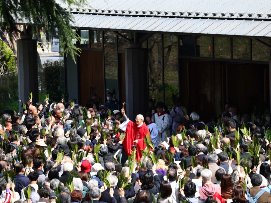 3/29(日)10:00- 受難の主日(枝の主日) 主聖堂前に集まるたくさんの会衆の棕櫚の葉に祝福の潅水をする髙祖神父